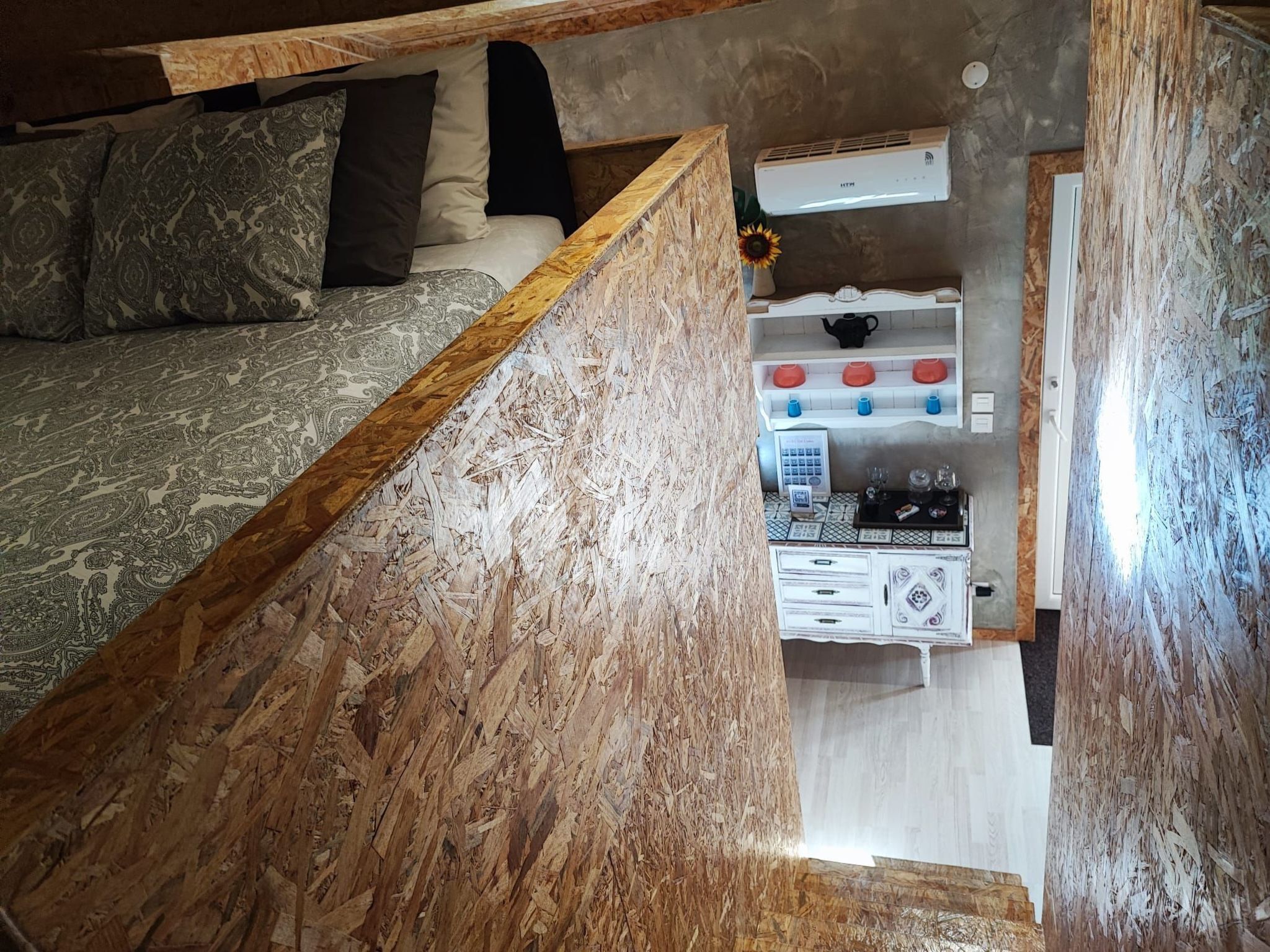 Een ruimtelijk ingerichte leefruimte met een bed, kitchenette en een kleine eethoek.