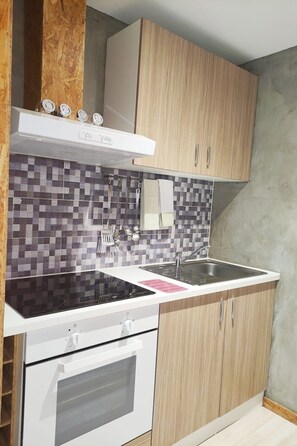 Een keuken met een zwart fornuis, een witte oven en een betegelde spatwand.