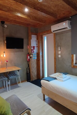 A room with a bed, a desk, a chair, a television, and an air conditioning unit. - Rubin Charme Häuser 9 by Interhome (Porto)