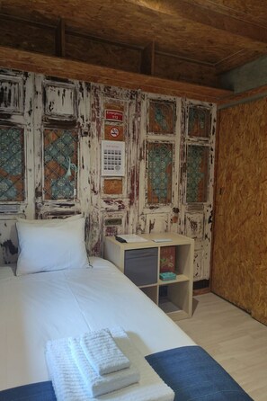 Een kamer met een bed, een nachtkastje en een muur met borden voor vluchtwegwijzingen.
