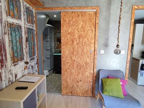 A room with a wooden door, a blue sofa with a green pillow, and a desk with a keyboard. - Rubin Charme Häuser 9 by Interhome (Porto)