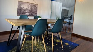 Un comedor con una mesa de madera, sillas color turquesa y un cuadro colgado en la pared.