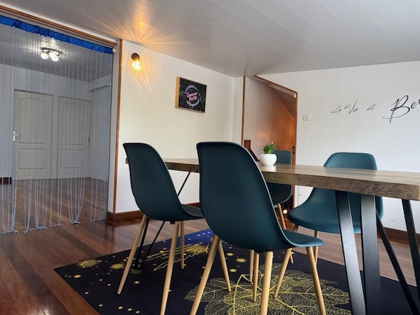 A dining area with a wooden table, teal chairs, and a wall-mounted light fixture.