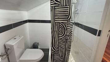 Ein Badezimmer mit Dusche, Toilette und Bidet.