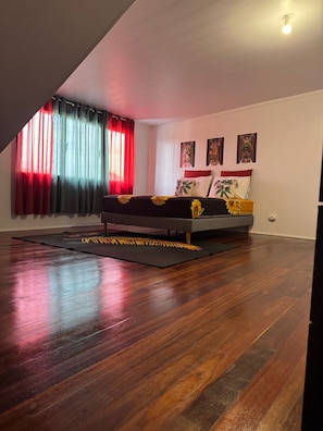 A bedroom with a bed, a window with curtains, and a wall-mounted light fixture.