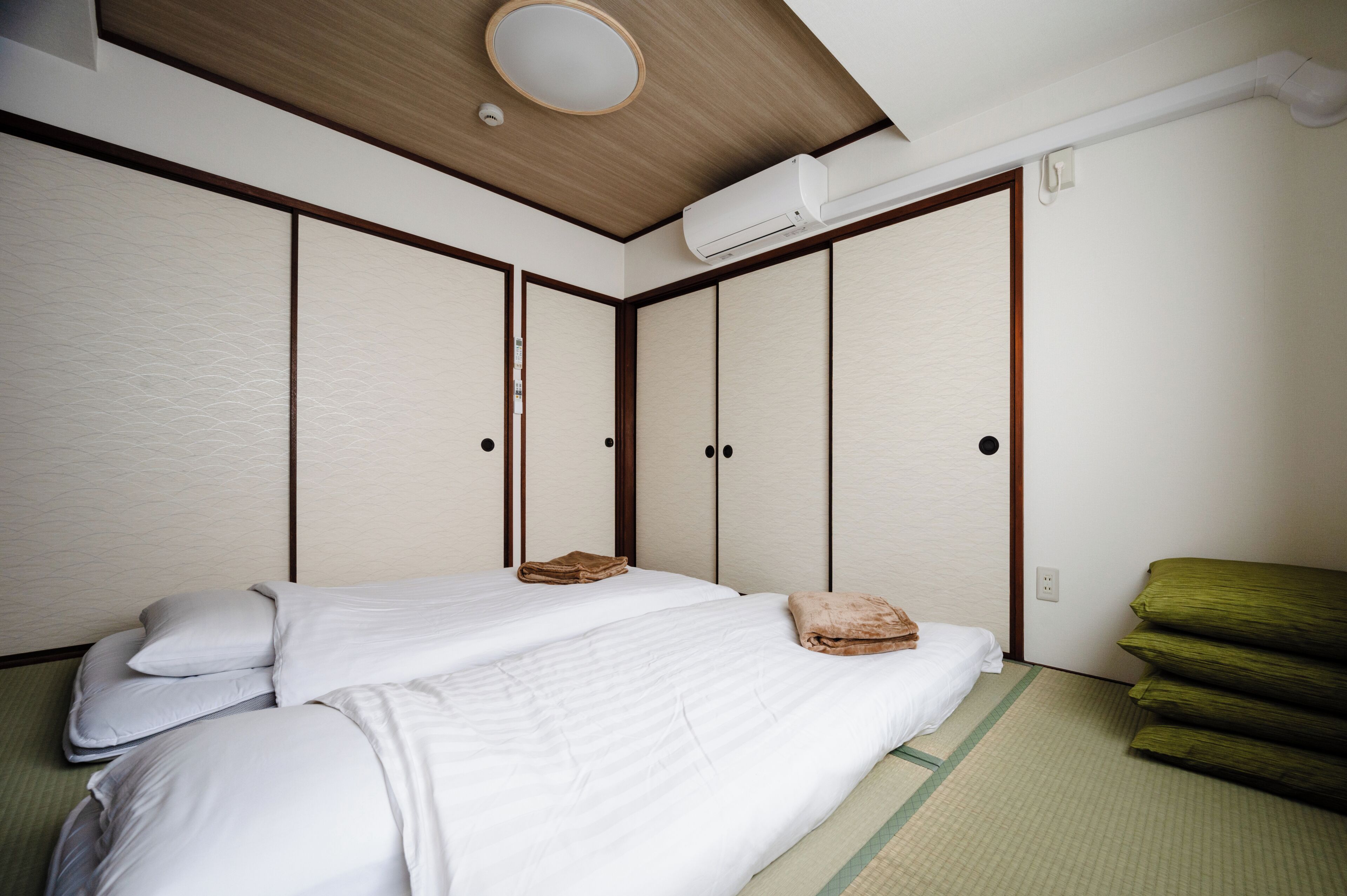A traditional Japanese-style bedroom with a bed, futon, and sliding doors.