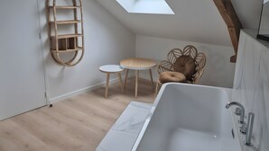 Uma casa de banho moderna com um claraboia, uma banheira independente e uma pequena mesa redonda com cadeiras.