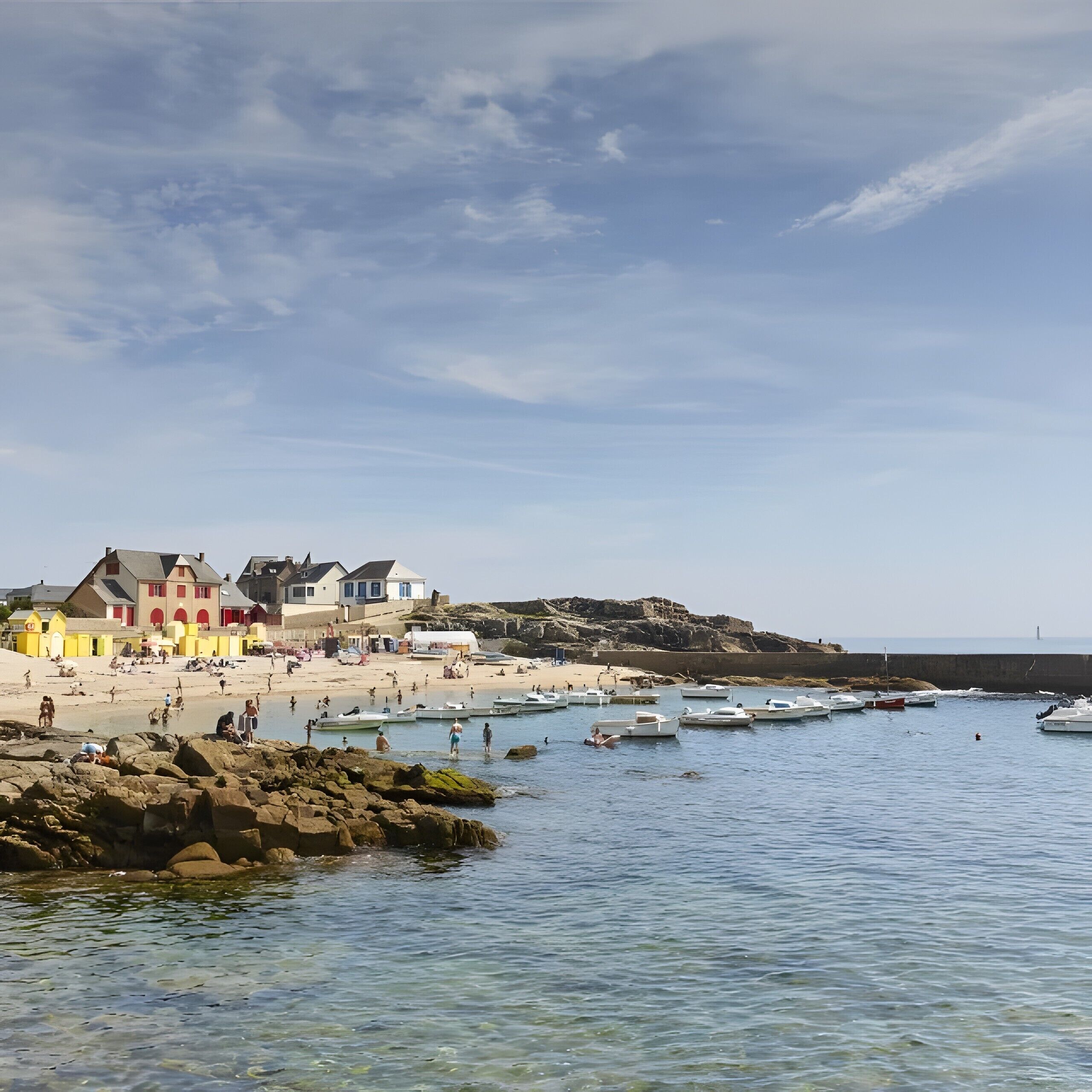 A coastal town with buildings along the shore, clear water, and boats.