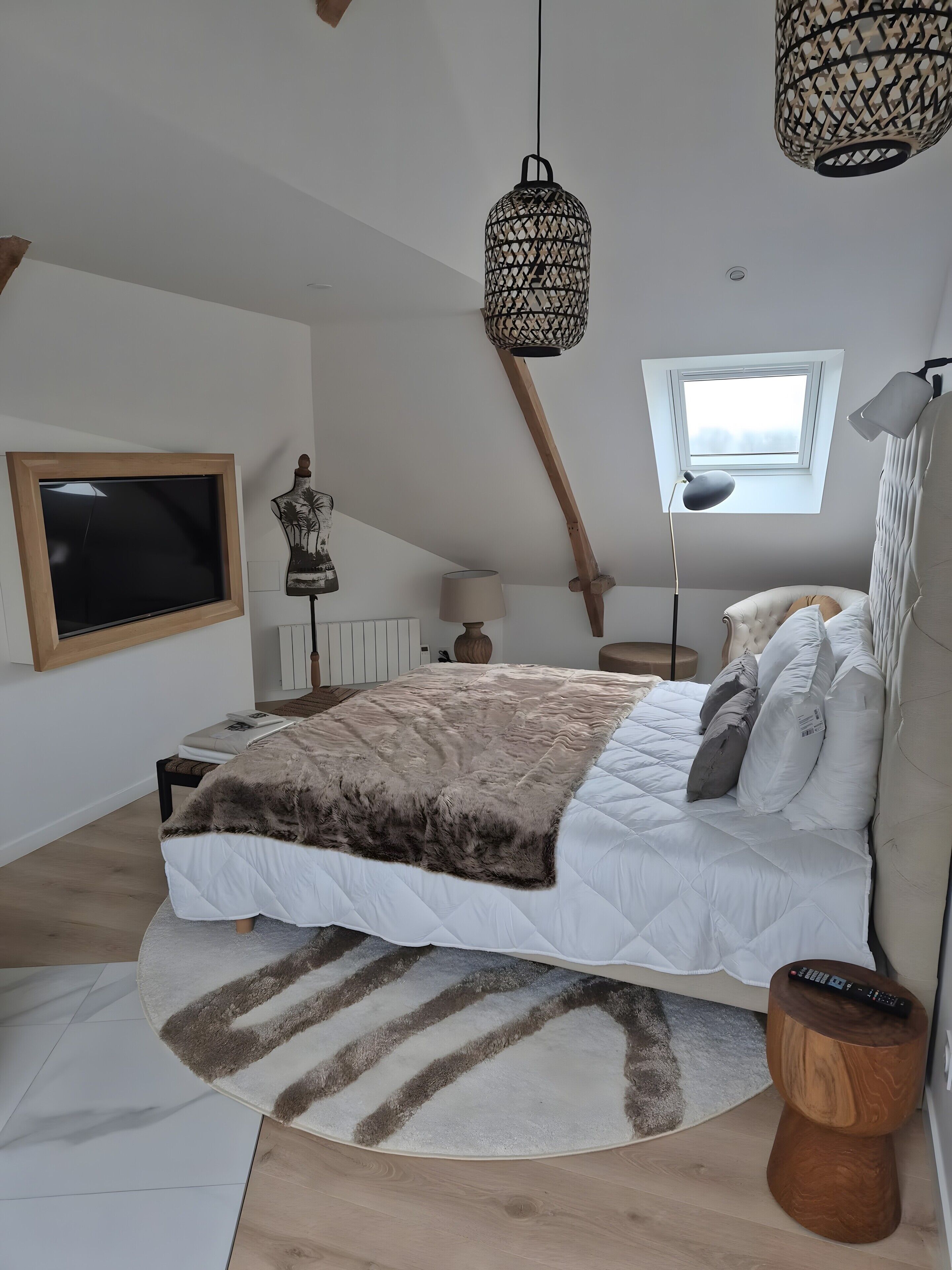 A bedroom with a bed, a TV, a window, a lamp, and a ceiling light fixture.