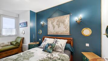 Une chambre avec un lit, un canapé vert, une carte accrochée au mur et un globe terrestre.