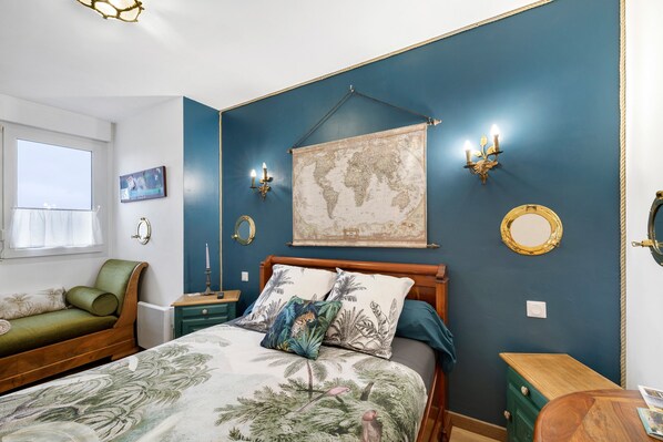 A bedroom with a bed, a green sofa, a map on the wall, and a globe.
