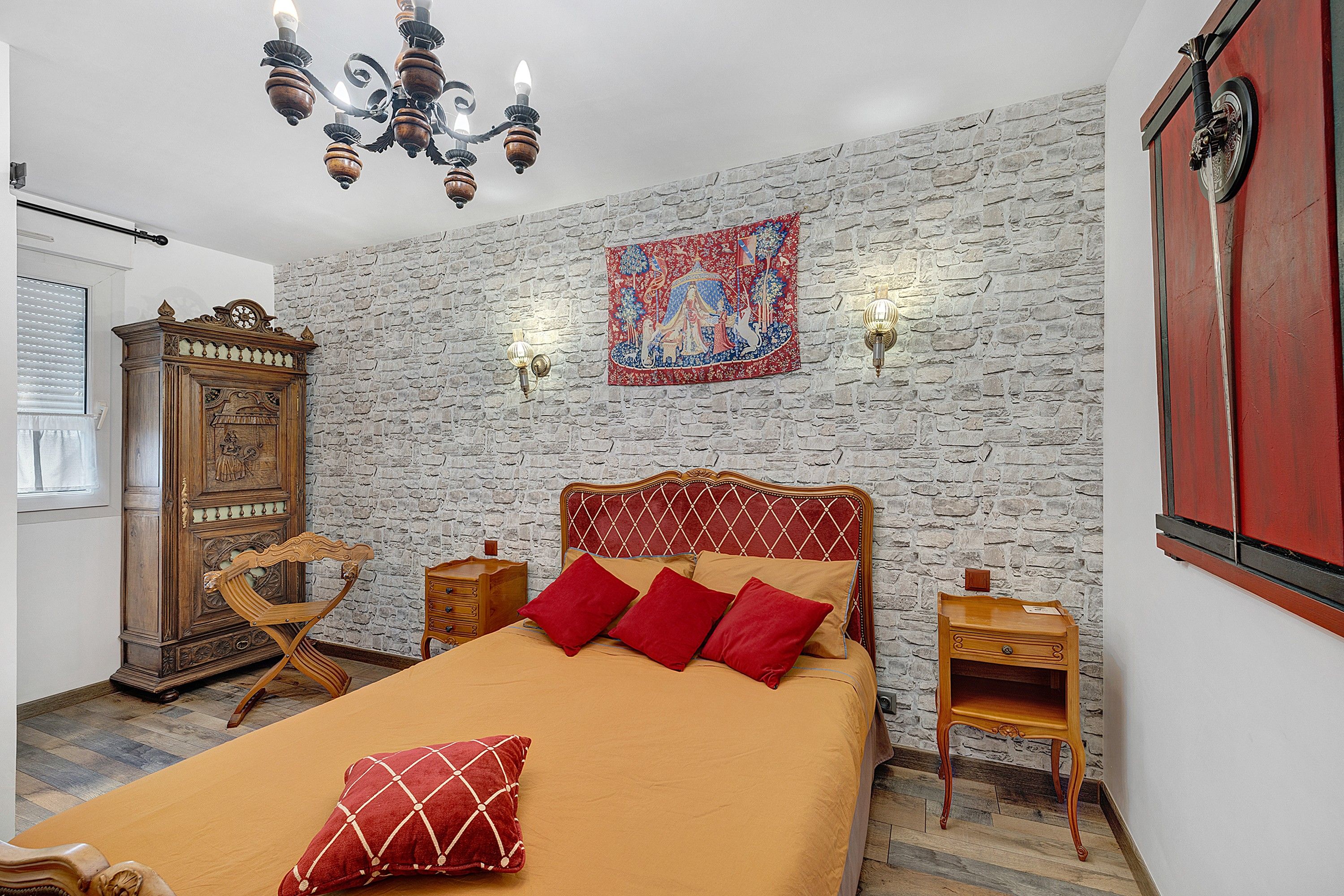 Quarto com cama, móveis de madeira, relógio de parede e tapeçaria.