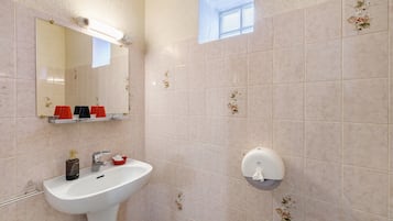 A bathroom with a sink, mirror, and hand soap dispenser.