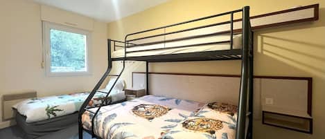 Une chambre avec un lit superposé, une fenêtre, un bureau et une chaise.
