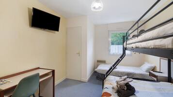 Une chambre de dortoir équipée de lits superposés, d’un bureau, d’une chaise, d’un téléviseur et d’une fenêtre donnant sur un paysage verdoyant.