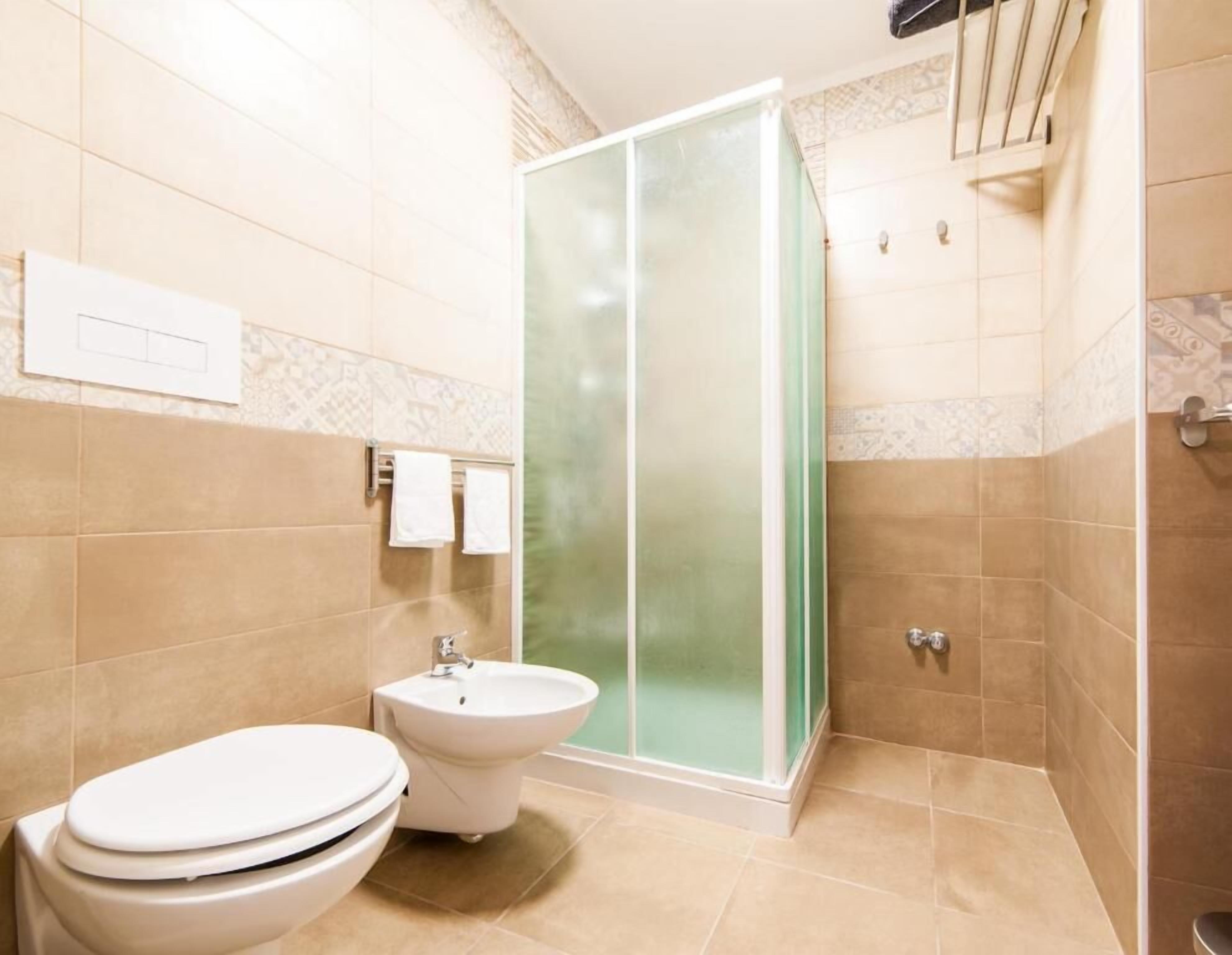 A bathroom with a toilet, bidet, and a glass-enclosed shower.