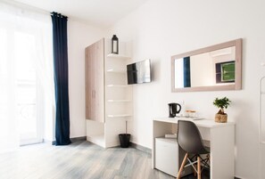 A modern, well-lit room with a desk, chair, and a large mirror. - Demi Rooms (Naples)