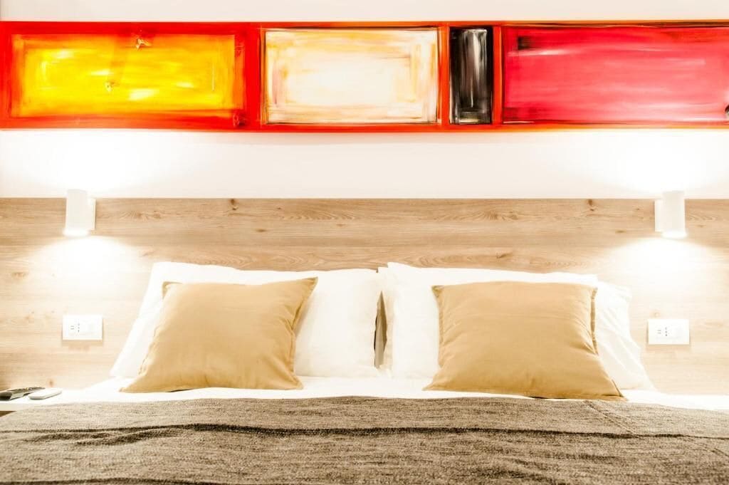 A bed with two pillows, a wooden headboard, and a wall with three rectangular artworks.