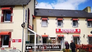 A building with a sign for 'Captain Cook' restaurant, a parking sign, and a directional sign for parking.