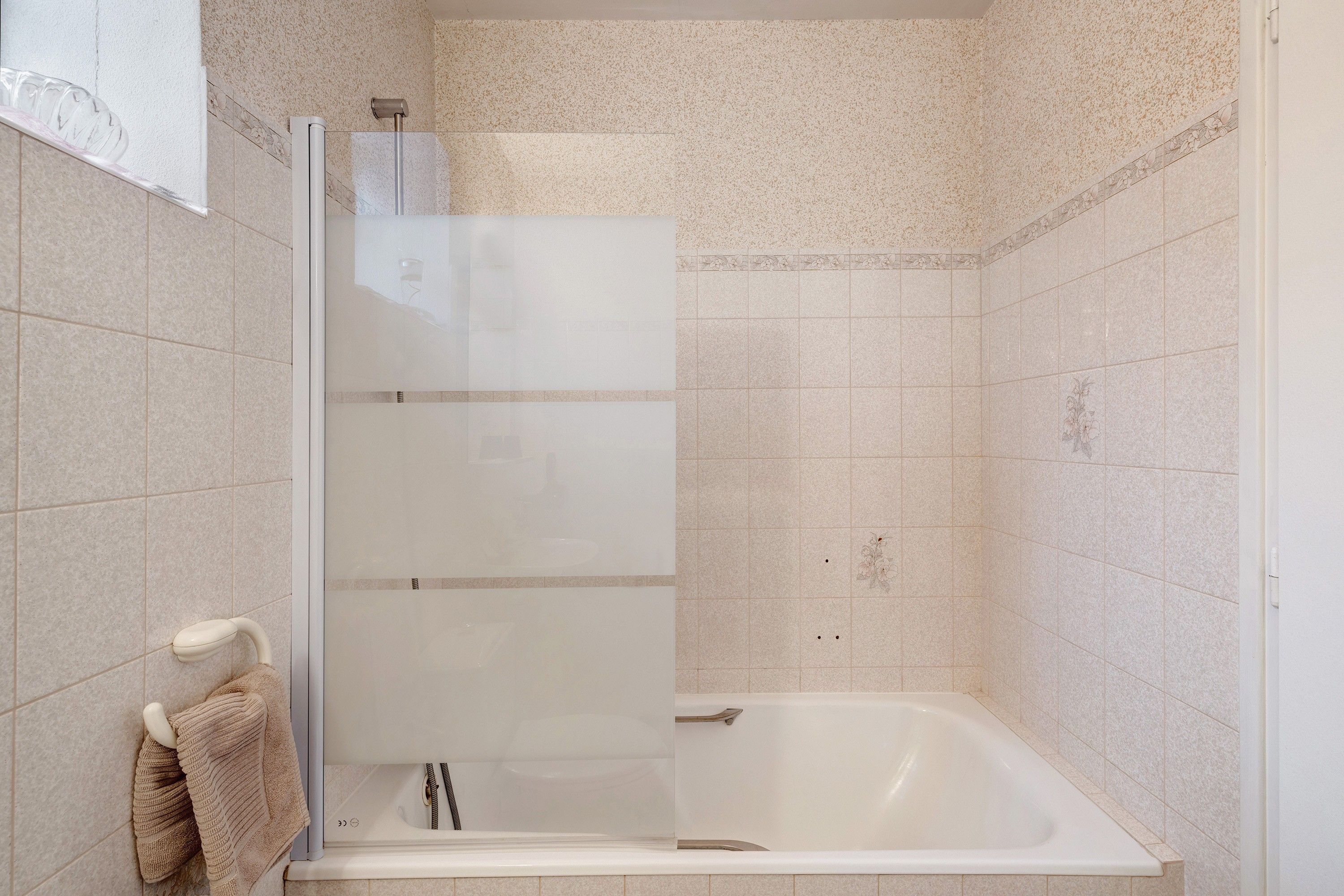 Een badkamer met een douchecabine, een bad en een handdoekhouder.
