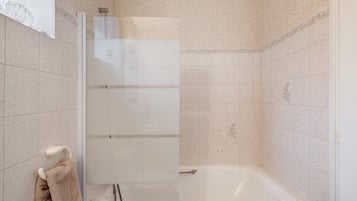 Een badkamer met een douchecabine, een bad en een handdoekhouder.