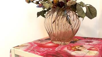 Un jarrón con flores secas sobre una mesa con mantel floral.