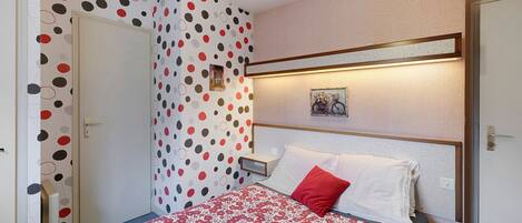 Ein Hotelzimmer mit Bett, Nachttisch, einem Wandbild und einer Tür.