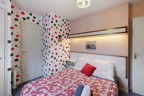A hotel room with a bed, a nightstand, a wall-mounted picture, and a door.