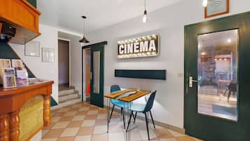 Une salle de cinéma avec un sol à carreaux, une table en bois et des chaises bleues.