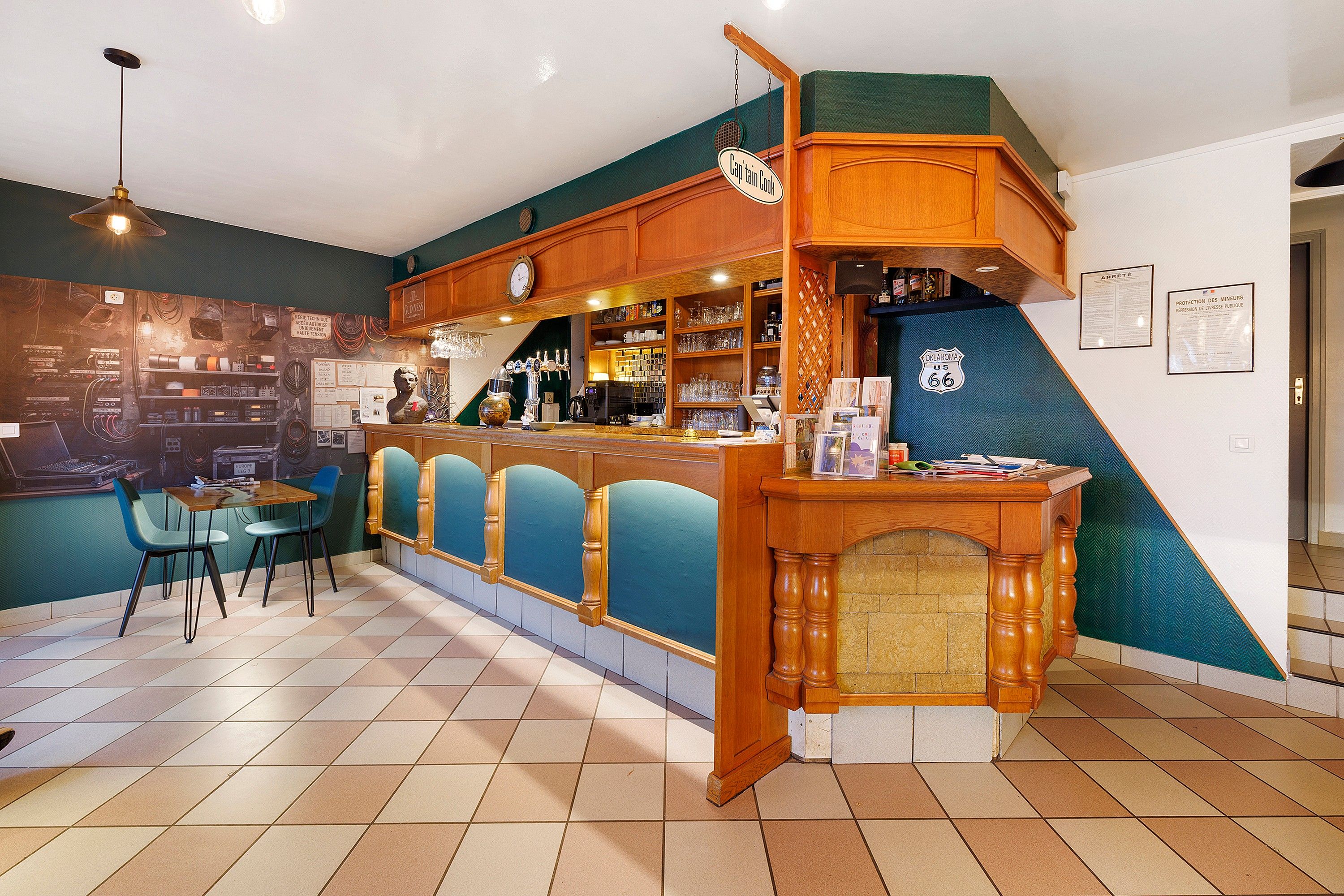 Eine Bar mit einer Holztheke, blauen Barhocker und einer Wanduhr.