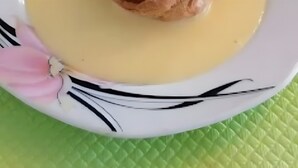 Postre en un plato con salsa cremosa, cobertura de chocolate y una cucharada de crema.