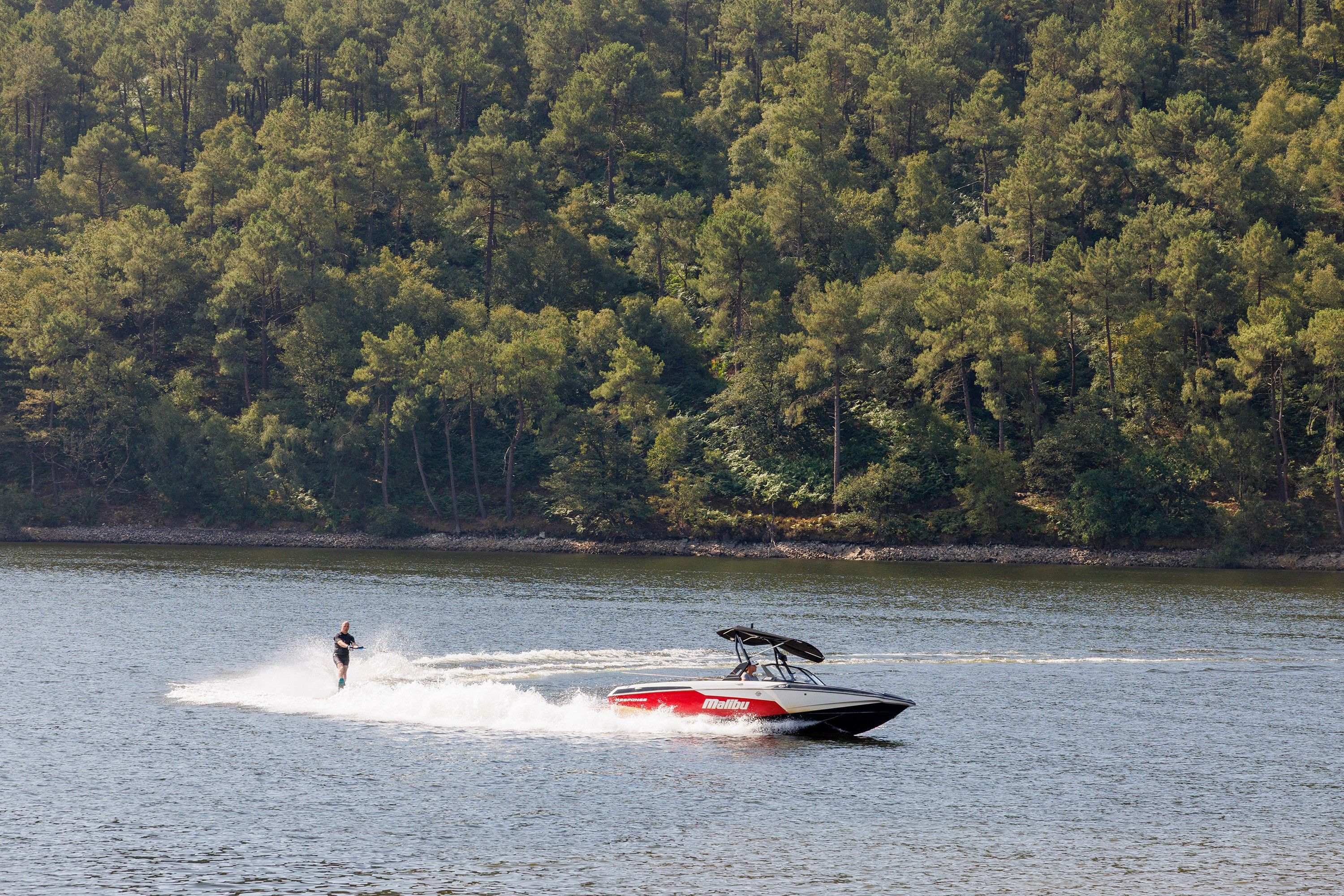 A water sport activity on a lake with a forested shoreline.