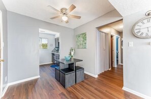 A hallway with a ceiling fan, a clock, and a dining area with a table and chairs.