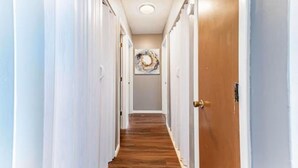 A hallway with white doors, a wooden floor, and a ceiling light. - Spacious & Convenient El Dorado Apt #5 (El Dorado)