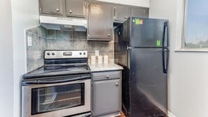 A compact kitchen with a built-in oven, a refrigerator, and a microwave. - Spacious & Convenient El Dorado Apt #5 (El Dorado)
