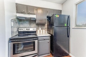 Eine kleine Küche mit Backofen, Kühlschrank und Mikrowelle.