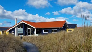 A modern house with a red roof, a large window, and a pathway leading to it. - Helles Kustenhaus mit Sauna (Grossenbrode)