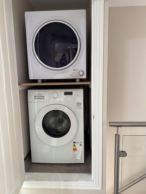 A compact laundry room with a Bosch washing machine and a Reemex dryer stacked on a shelf.