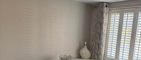A bedroom with a bed, a dresser, a chair, and a window with blinds.