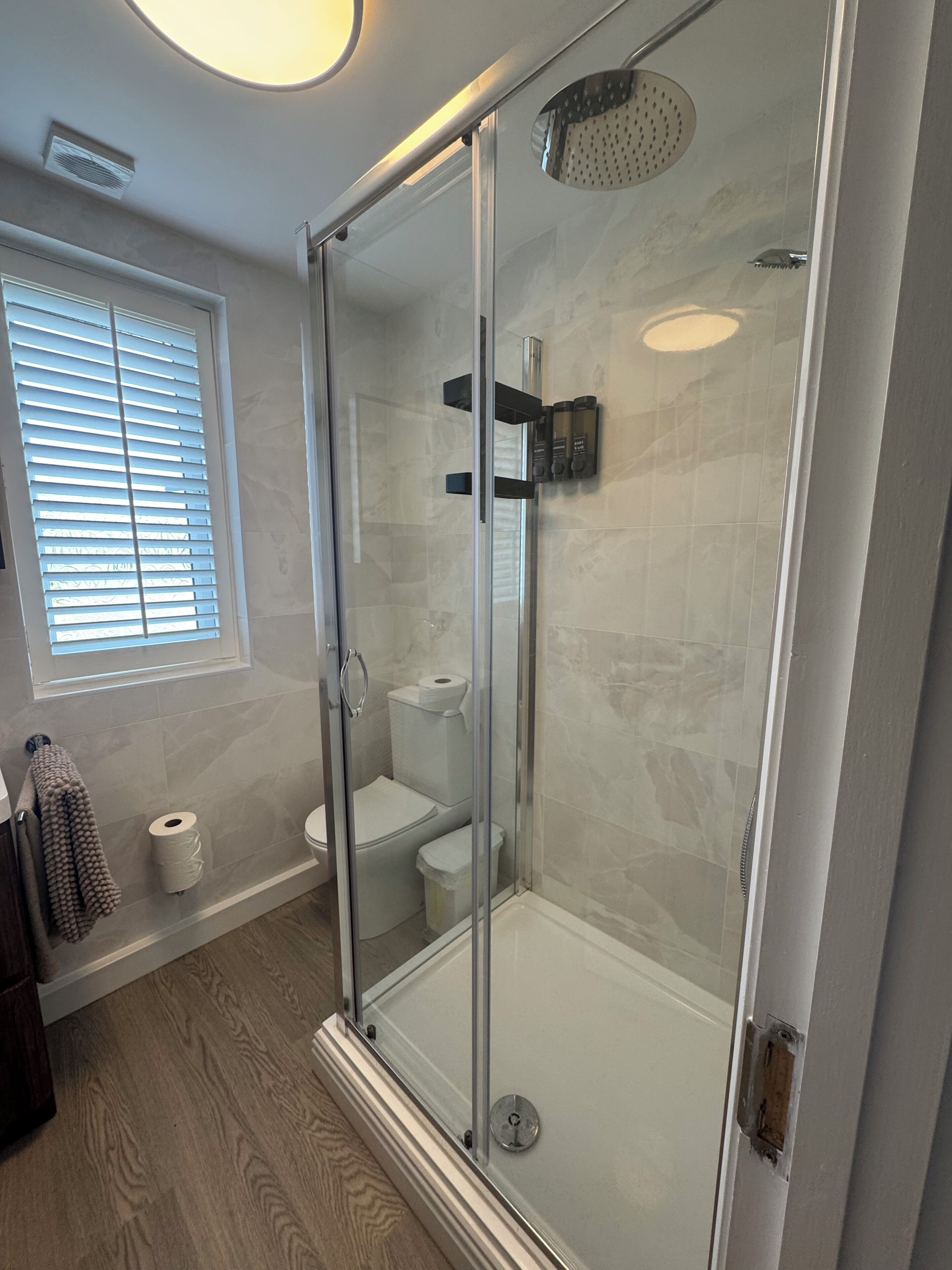 A modern bathroom with a glass-enclosed shower, a toilet, and a towel rack.