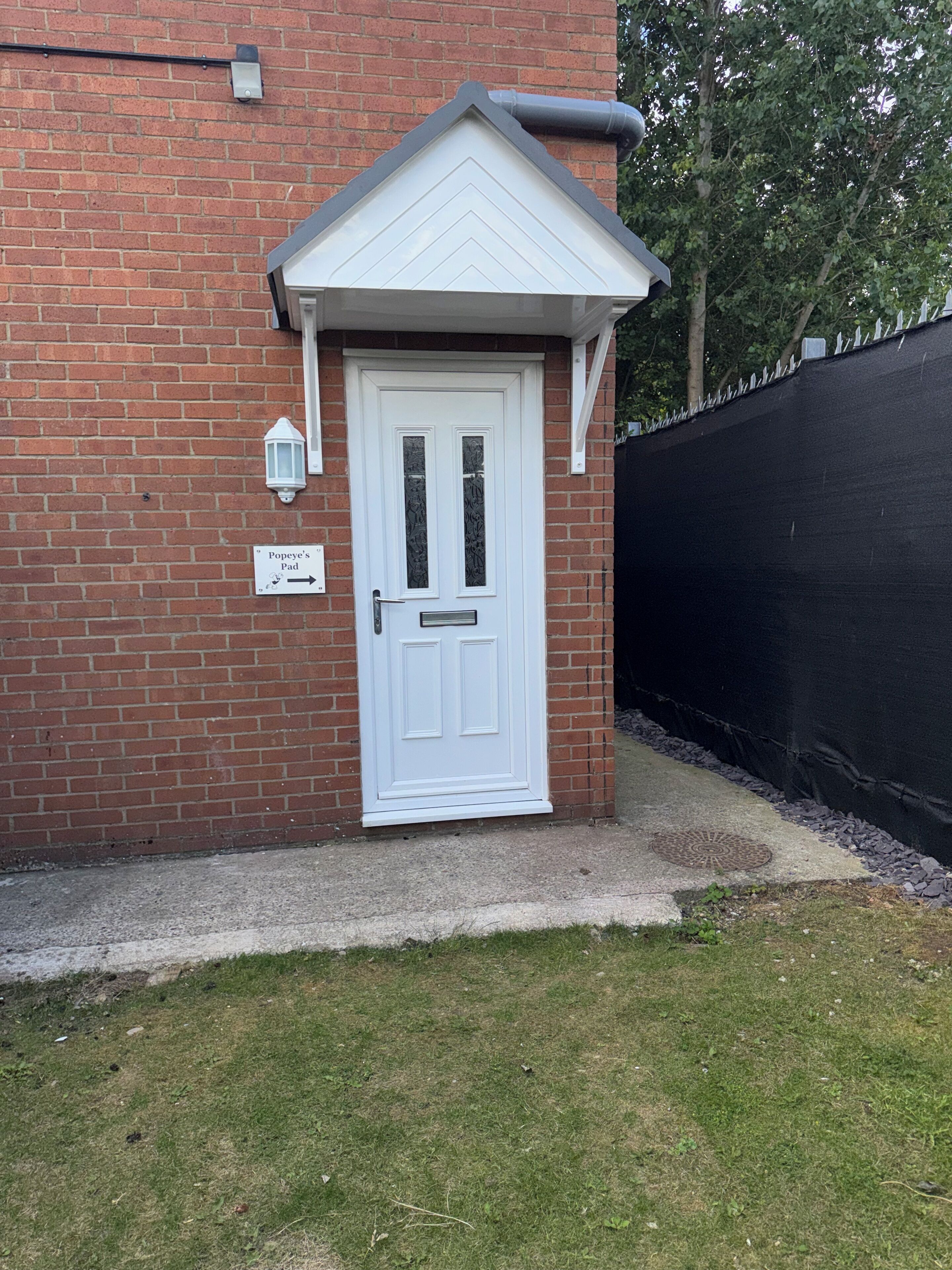 A white door with a small porch and a brick wall.