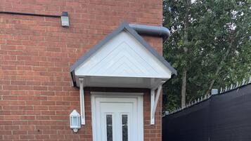 A white door with a small porch and a brick wall.
