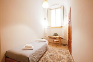A small, well-lit bedroom with a single bed, a desk, and a chair. - Elegant 2BR Apartment (Firenze)