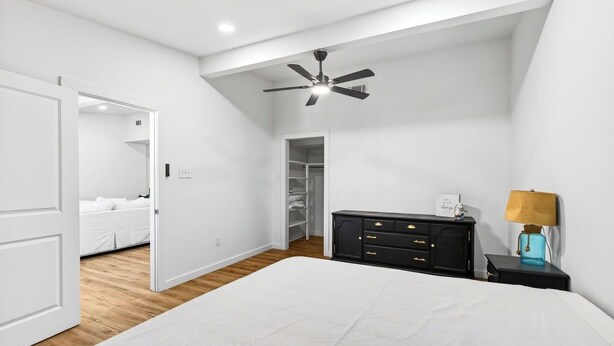 Un dormitorio con cama, armario, mesita de noche, lámpara y ventilador de techo.
