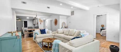 A spacious living area with a sofa set, a coffee table, and a teal cabinet.