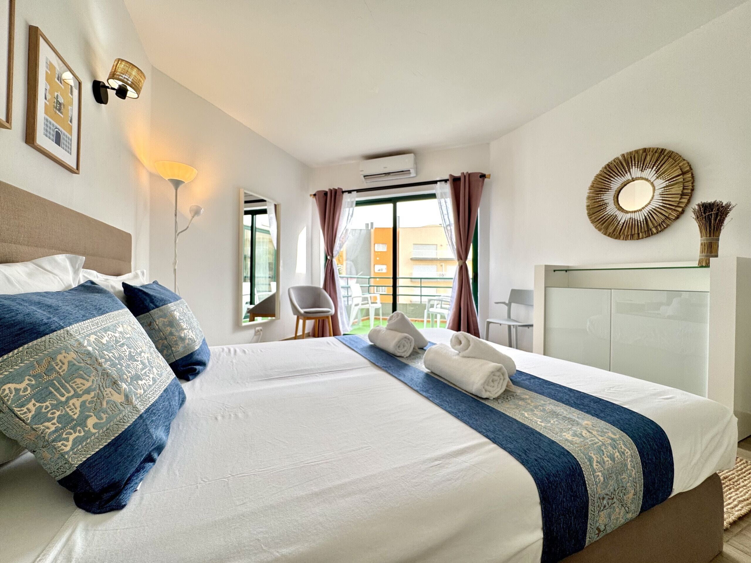 Une chambre d’hôtel avec un lit, une chaise, un bureau, un miroir et une vue sur l’extérieur.