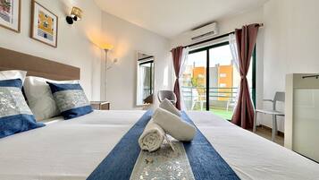Habitación de hotel con una cama grande, un escritorio, una silla, un balcón con vistas y aire acondicionado.