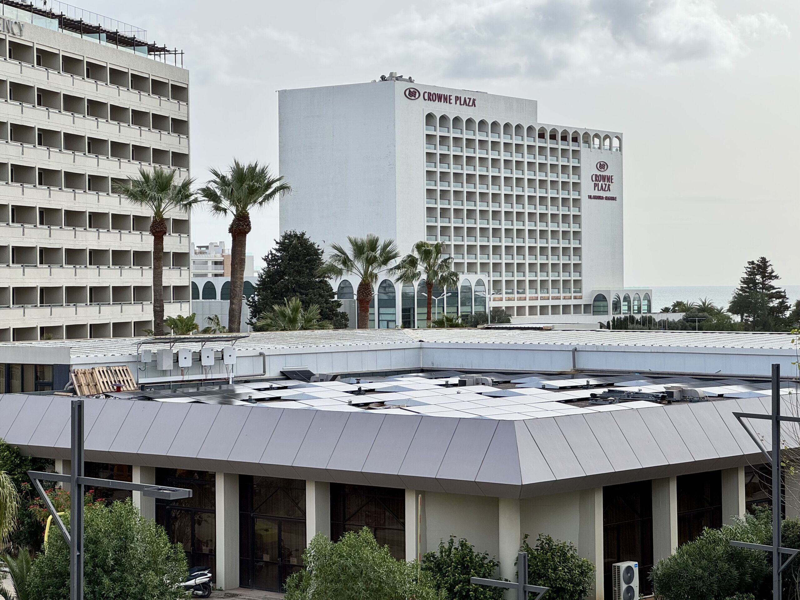Un hotel con terraza en la azotea, varios pisos y vistas al mar.