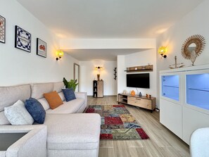 A modern living room with a sofa, TV, and decorative wall lights. - Vilamoura Central Beach 1 by Homing (Loulé)