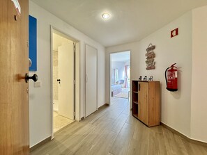 A hallway with wooden flooring, white walls, and a fire extinguisher mounted on the wall. - Vilamoura Central Beach 1 by Homing (Loulé)